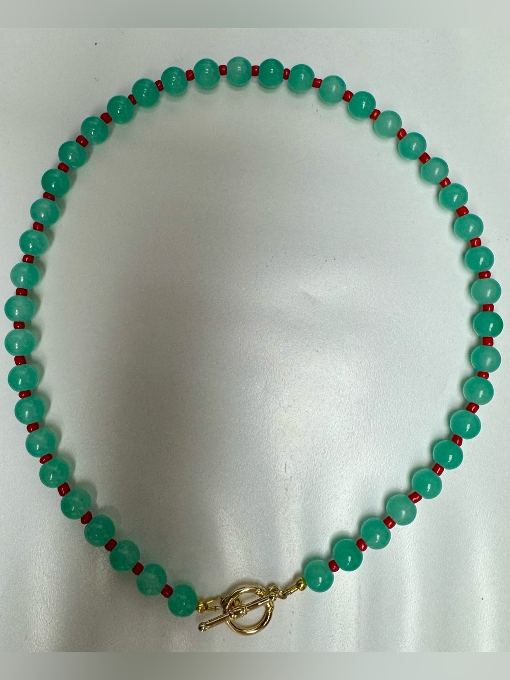 Green Beaded Necklace with Red Accents and Gold Toggle Clasp.